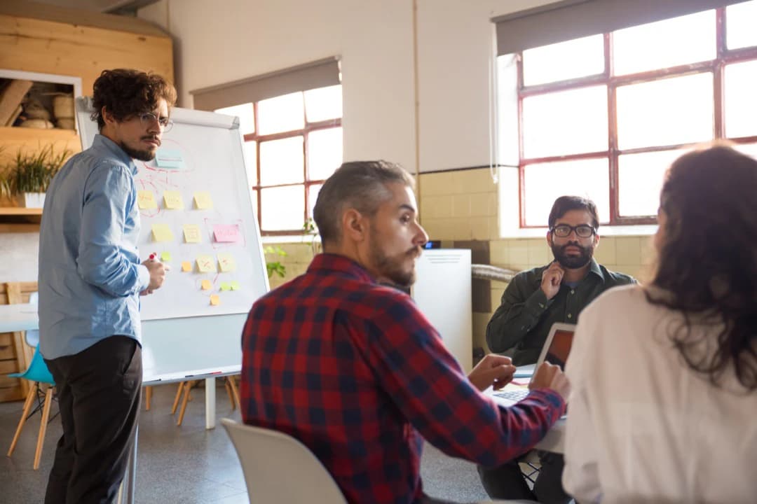 Un equipo revisando notas adhesivas en una pizarra durante una sesión de trabajo